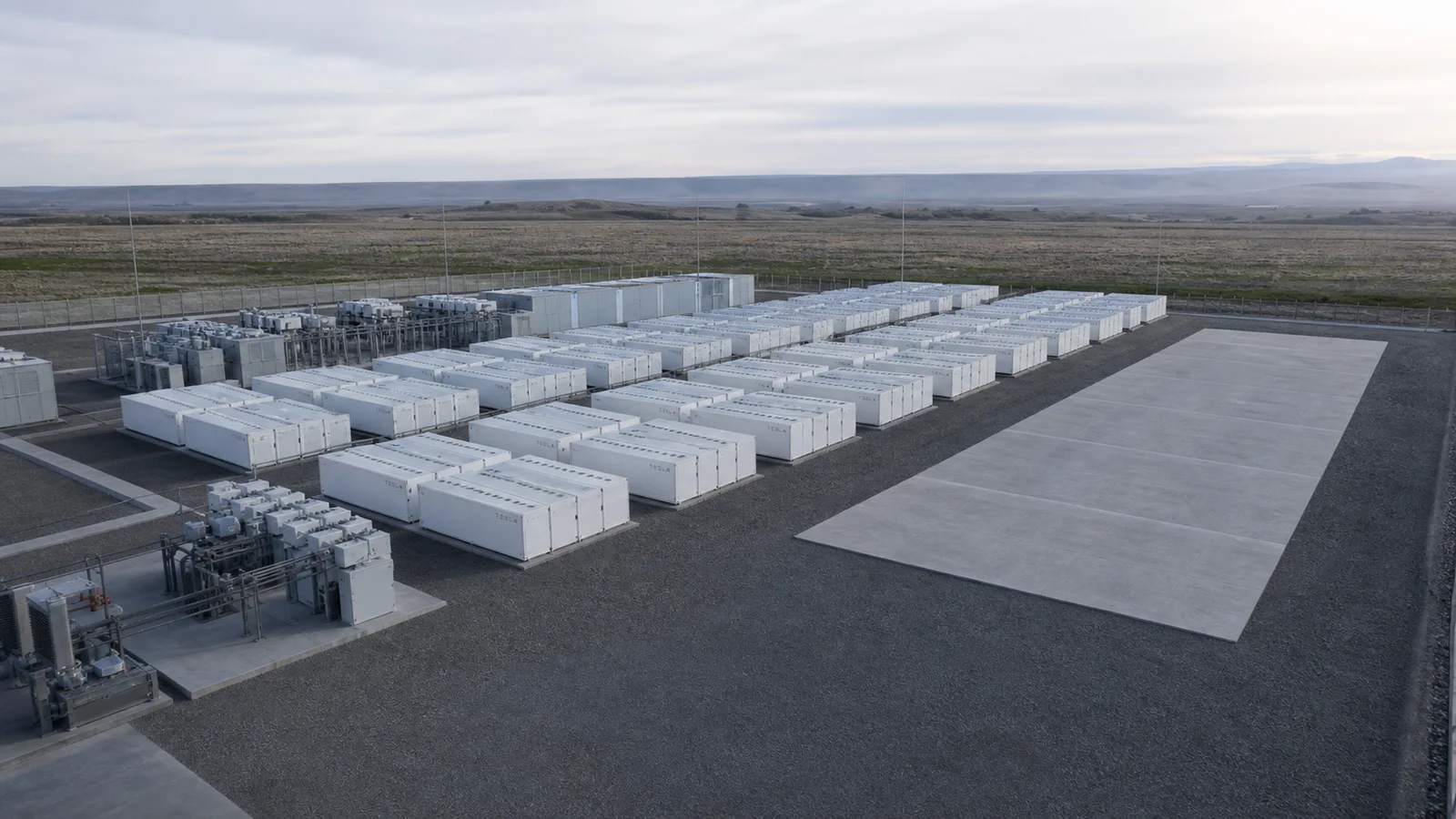Rows of source-grounded Tesla Megapack units beside an open expansion pad at a generic grid-storage site