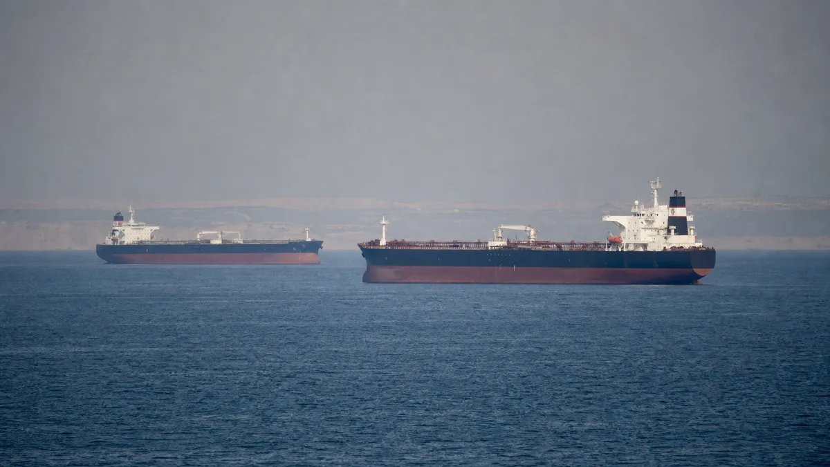 Commercial tankers move through hazy Gulf waters near a low shoreline