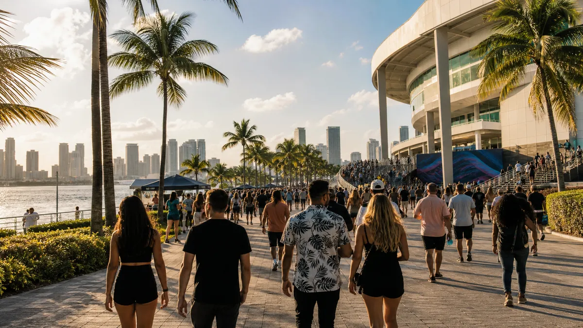Crowds walking near palm trees and a waterfront event venue in Miami.