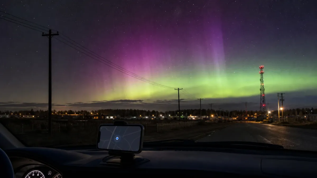 Aurora above a small town with power lines, a communications tower and a generic navigation screen