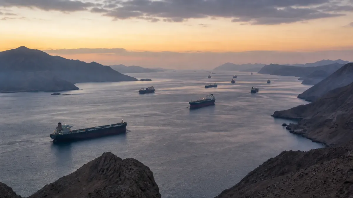 Editorial illustration of commercial ships moving through a narrow mountainous waterway at dawn