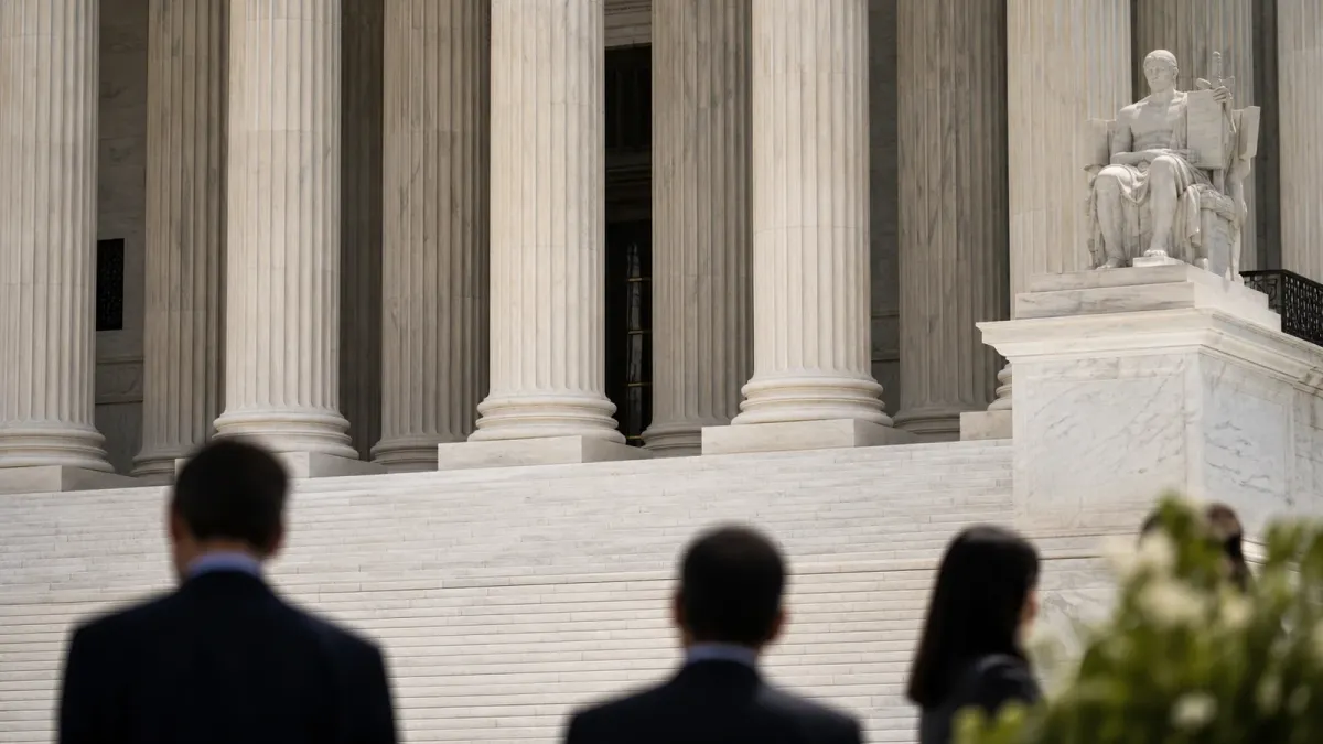 A courthouse entrance with stone columns and non-identifying figures in the foreground.