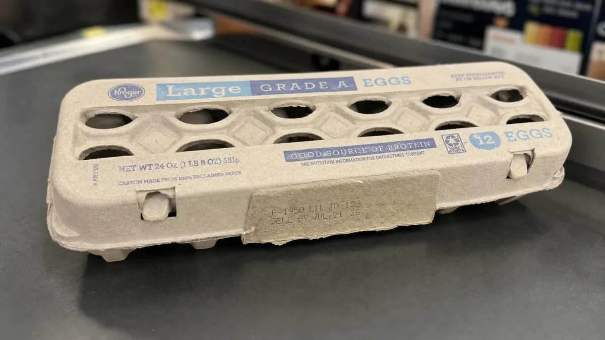 A Kroger Grade A egg carton on a dark counter with the side date-code area closest to the camera