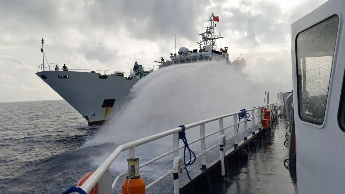 A source-grounded editorial image of a China Coast Guard vessel spraying water near a Philippine Coast Guard vessel at Scarborough Shoal.