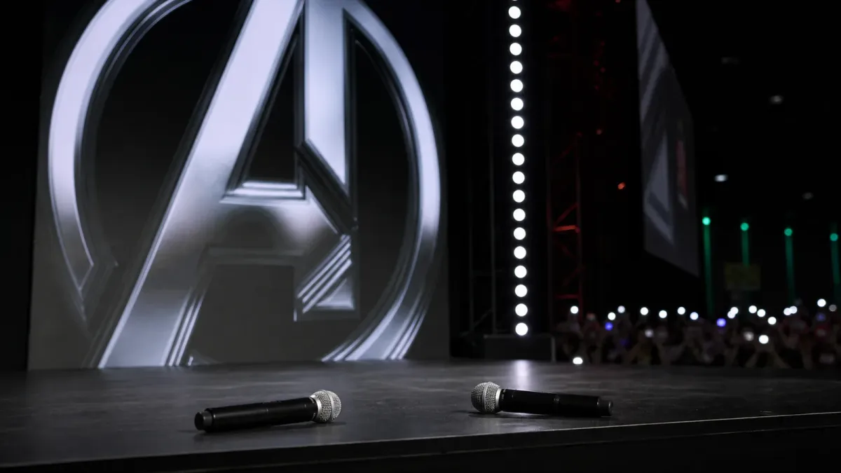 Marvel Studios Comic-Con stage setting with microphones and a large franchise screen behind them