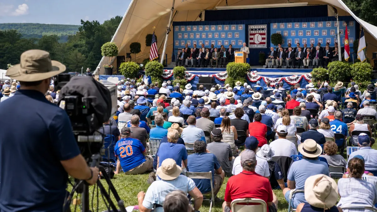 Outdoor Baseball Hall of Fame induction stage with fans gathered for the Cooperstown ceremony