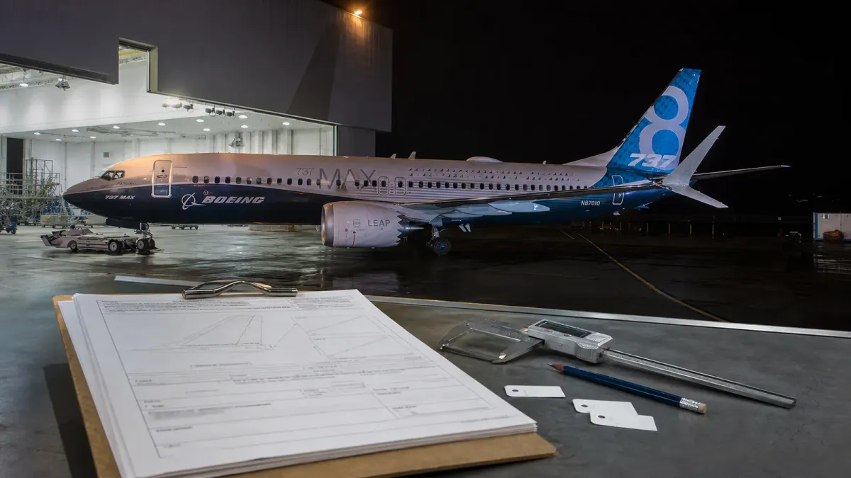 A Boeing 737 Max aircraft in a hangar with inspection documents and tools in the foreground