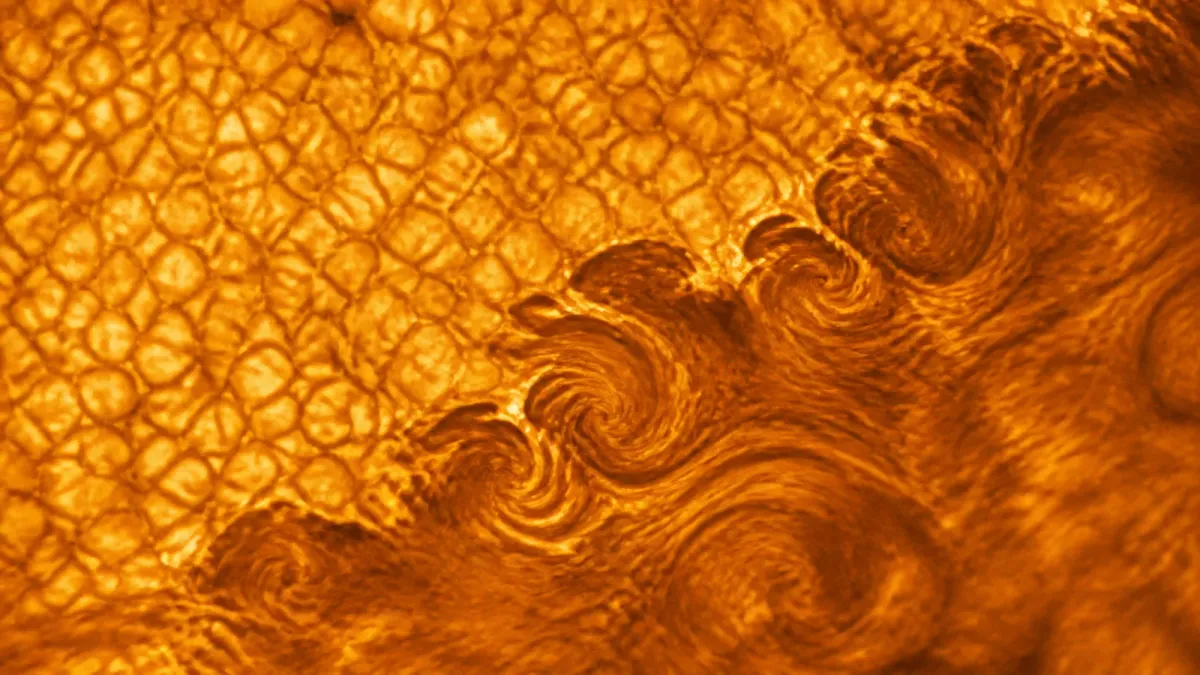 Source-grounded close view of the Sun's surface with fine dark striations curling between bright plasma granules.