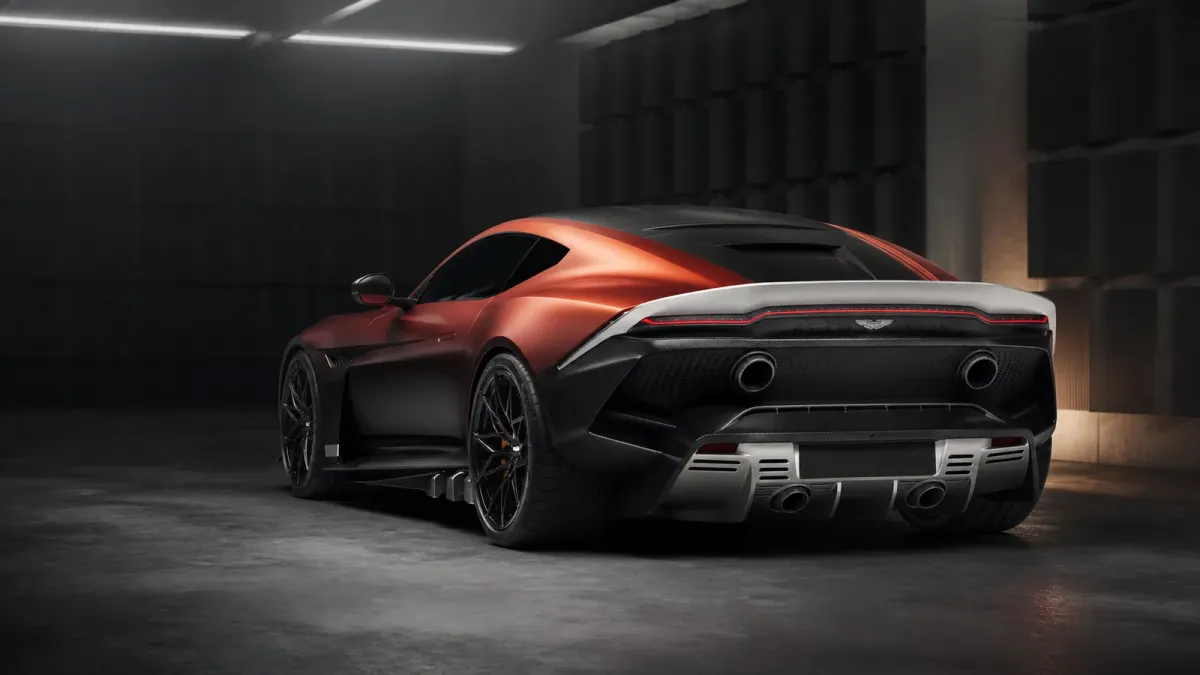 Copper-red Aston Martin Valen viewed from the rear in a staged acoustic test bay, emphasizing its carbon-fiber body and stacked quad exhaust.