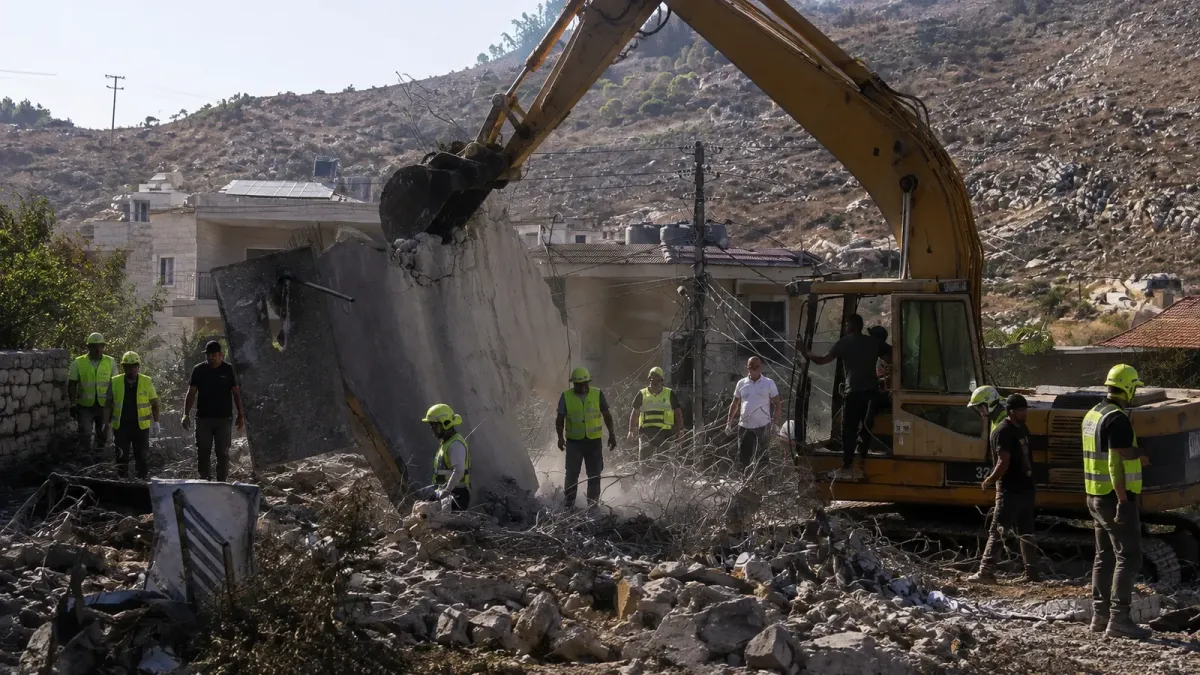 Responders and an excavator search the rubble of a collapsed building in Kfar Rumman after the September 7 strikes.