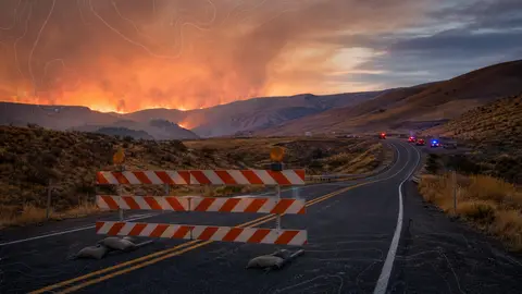 Generic editorial image of a wildfire evacuation road closure in dry hills