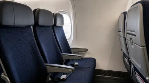 Editorial illustration of a generic airplane seat row positioned beside a blank cabin wall