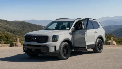 A Kia Telluride parked outdoors with a front door open and the front cabin visible.