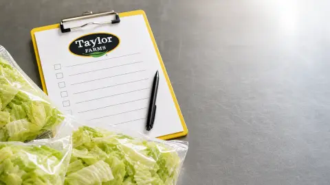 Taylor Farms recall worksheet beside pulled iceberg lettuce bags on a prep table