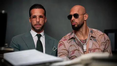 Andrew Tate and Tristan Tate in a neutral editorial portrait with blurred extradition paperwork in the foreground