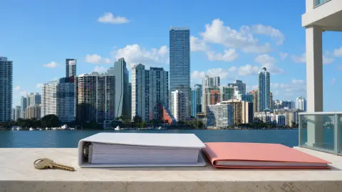 A property key and unmarked condo and permit folders on a ledge overlooking Miami's Brickell skyline