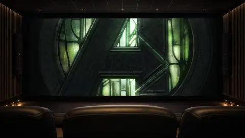 The metallic-green Avengers emblem fills a large cinema screen above rows of empty premium-theater seats