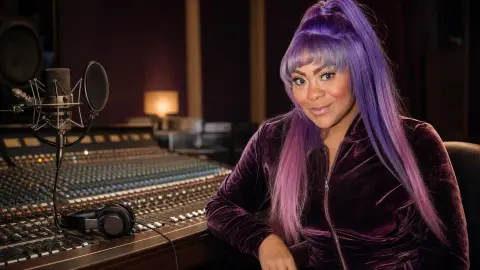R&B singer Nivea seated in a recording studio beside a microphone and mixing console