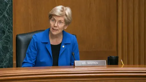 Elizabeth Warren speaks into a microphone at the Senate Banking Committee dais.