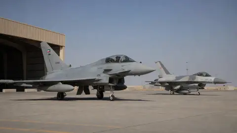 A Kuwait Air Force Eurofighter and Royal Bahraini Air Force F-16 on a neutral airbase apron in a source-grounded editorial image