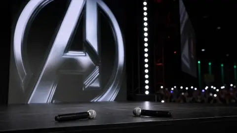 Marvel Studios Comic-Con stage setting with microphones and a large franchise screen behind them