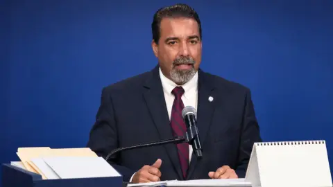 Rafael A. Villalobos at a microphone in a Miami-Dade schools transition-themed editorial image.