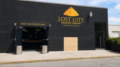 Lost City Brewing's North Miami facade shown with a temporary plywood repair area and clear sidewalk space.