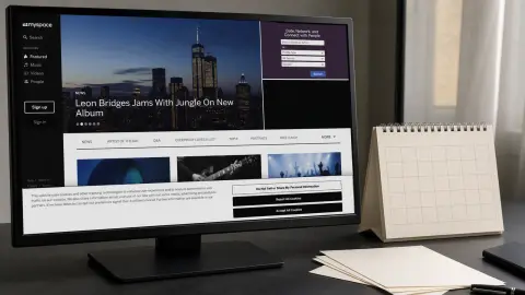 The current Myspace music and culture homepage displayed on a desktop monitor beside an undated blank calendar