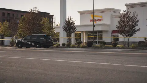 A source-grounded editorial view of the Twin Falls In-N-Out exterior behind a quiet police perimeter after the shooting