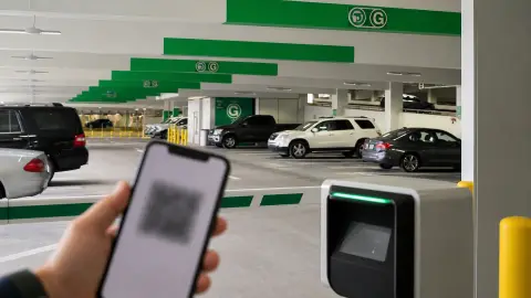 A Miami International Airport parking garage scene with a phone held near a gate scanner to represent prepaid garage entry.