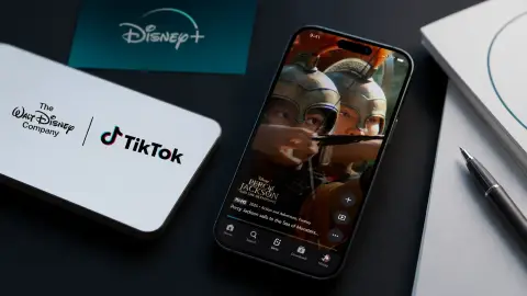 A phone with a Disney+ Verts-style vertical video screen sits beside a Disney and TikTok partnership reference and an earnings packet.