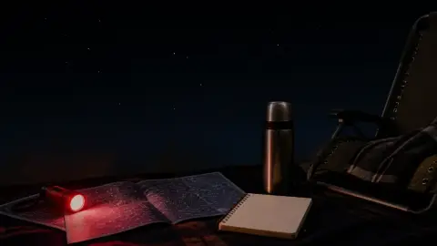 A blanket, red flashlight, notebook, and sky map arranged for a Perseid meteor shower viewing plan