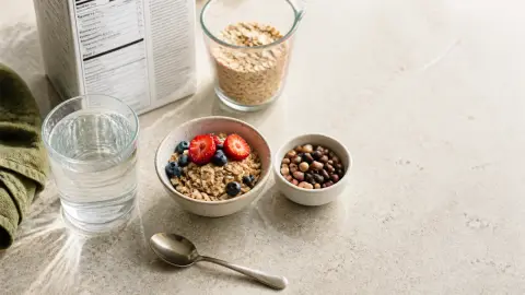 A kitchen counter with oats, berries, beans, water, and a generic nutrition label arranged as a gradual fiber-choice setup.