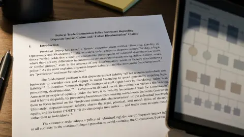 Federal Trade Commission policy document on a desk beside a generic automated-decision screen reflection