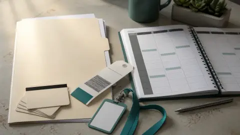 Airport luggage tags, hotel key cards and blank work authorization paperwork arranged beside an empty staff schedule