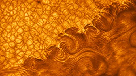 Source-grounded close view of the Sun's surface with fine dark striations curling between bright plasma granules.