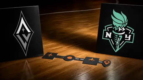Las Vegas Aces and New York Liberty logos face each other across an empty basketball court with travel-route markers between them.