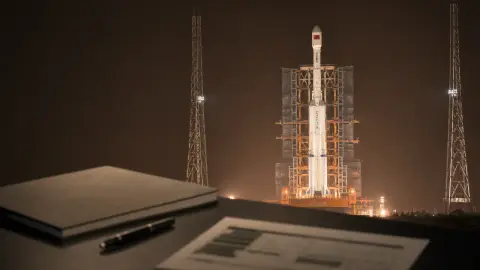 A source-grounded editorial view of a Long March 7A rocket with mission-review materials in the foreground.