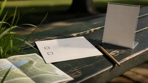 A generic ballot card, pencil, park map and blank ad placard arranged on a park bench.
