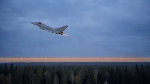An Italian Eurofighter climbs above a Baltic air base at dawn in an editorial image about Latvia's airspace alert