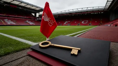 Liverpool's red corner flag at Anfield beside a large brass key and two blank document folios symbolizing retained control and new minority investment