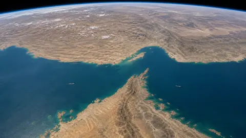 Orbital view of the Strait of Hormuz between Iran and Oman's Musandam Peninsula with a few merchant ships visible