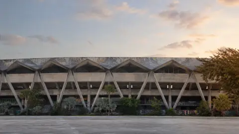 Weathered folded concrete roof and V-shaped supports of Miami Marine Stadium in soft dawn light
