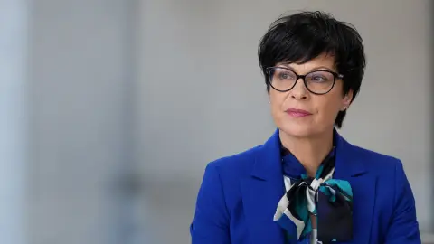 AI-generated editorial portrait of EU enlargement commissioner Marta Kos, who canceled her planned Serbia visit.