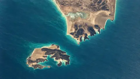 AI-assisted historical aerial view of Mayun island beside the Yemeni peninsula in the Bab el-Mandeb Strait.